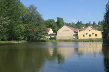 pohled přes Návesní rybník na okraji zámeckého parku na hospodářské budovy (© Jaroslav Špiroch, 05/2018)