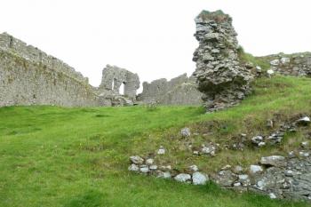 Pohled přes vnitřní prostor hradu k severní věži.  Na popředí je zeď terasy a hned za ní pozůstatky čtverhranné stavby s cisternou na dešťovou vodu. (© Pavel Semple, 08/2015)