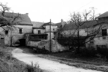 Pohled na jihovýchodní nároží nádvoří se zámkem někdy po r. 1945. Uprostřed přístavek schodišťové věže a na ní navazující křídla zámecké části areálu. Vlevo průjezd brány východního křídla, zcela vpravo mlýnice. Mezi mlýnicí a schodišťovou věží je dřevěná (© Fotoarchiv NPÚ, ú.o.p. Brno)
