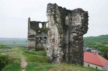 Polygonální bašta (nalevo) a zachovalá část západní hradby (napravo). Na popředí stojí palácová příčka. Dole napravo je střecha zámku z 19. stol. (© Pavel Semple 04/2019)