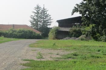 Pohled na místo zámku od vstupní brány na severu. Vzadu stará hosp. budova (© Dušan Dohňanský 07/2019)
