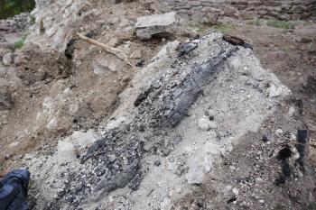 Ohořelé trámy na suti zdiva svědčí o násilné destrukci a požáru trojúhelné věže. (© Pavel Semple 04/2019)