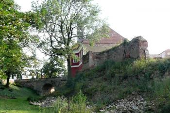 torzo obvodového zdiva zaniklých částí zámku a pohled na branskou věž a most v pozadí ( © Jan P. Štěpánek 08/2011)