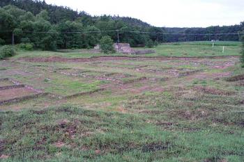 Odkryté zdivo zástavby, za ní mstěnická tvrz ( © Roman Řezáč 07/2004)