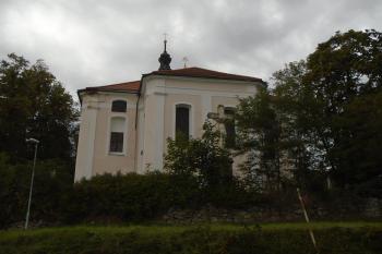 pohled na uzávěr (presbytář) kostela z východu; vpopředí, zastíněn stromy kamenný kříž (© Jaroslav Špiroch  09/2022)
