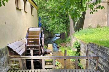 Pohled z mostku přes náhon na stavidla s obnoveným mlýnským kolem (© Jan P. Štěpánek  05/2024)
