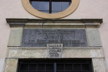 Nápisová deska nad hlavním portálem, připomínající zásluhy císaře Josefa II. na stavbě kostela ( © Ivan Grisa 11/2009)