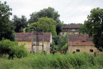 Pohled na zámek od řeky, v popředí se nelézají budovy statku, v zadu samotný zámek (© Jana Pertlíková, 07/2013)