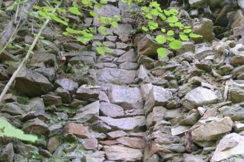 Úzký líc vnější hradby (pohled zvnějšku), který tvoří (tvořil) snad nějakou šachtu dosedající na skálu (© Jan Večeřa, 09/2014)
