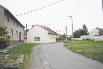 pohled na č.p. 223 ( v popředí vlevo ) příkop ( silnice a travnatá plocha nad ní) a možný zbytek vnějšího valu ( v pozadí při kamenné zdi) ( © Ondřej Štěpánek 06/2006)