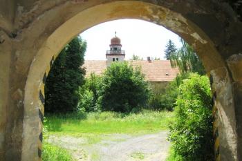 Vstup do zpustlého dvora, v pozadí chátrající budova zámku ( © Filip Matoušek 07/2006)