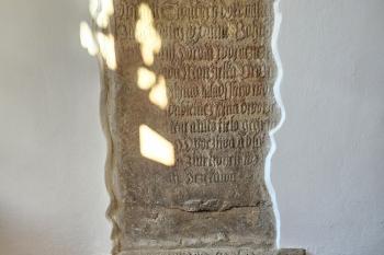 kamenný náhrobník a část nápisové kamenné desky v předsíni kostela (© Jan P. Štěpánek  01/2025)