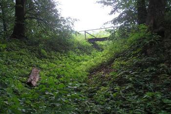 přechod západního příkopu v severní, v pozadí můstek do jádra hrádku ( © Ondřej Štěpánek 06/2006)
