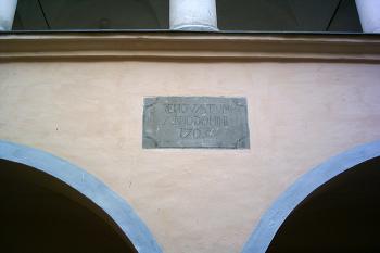 Arkády v přízemí zámeckého nádvoří s deskou na cviklu nad prostředním pilířem s nápisem pocházejícím z roku 1705, upozorňující na opravy po velkém požáru (© Miroslav BITTER 07/2005)
