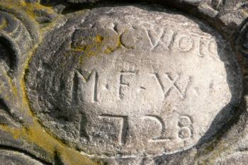 Kamenný medailon na podstavci sochy sv. Jana Nepomuckého z roku 1728, stojící na konci bývalého staroměstského shromaždiště splaveného dřeva u cesty z Frýdku do Bašky ( © Jan P. Štěpánek 11/2009)