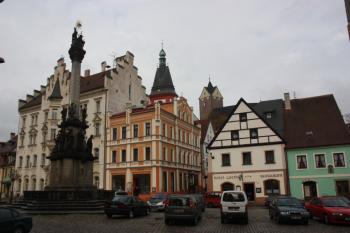 Střed severní fronty náměstí, v popředí trojiční sloup, v pozadí věže kostela a hradu ( © Ivan Grisa 11/2009)